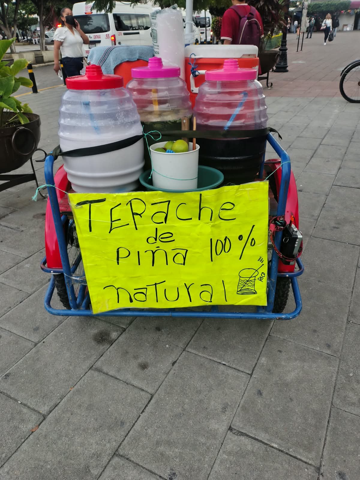 Carrito de bebidas en la calle con cartel amarillo de tepache de piña 100% natural